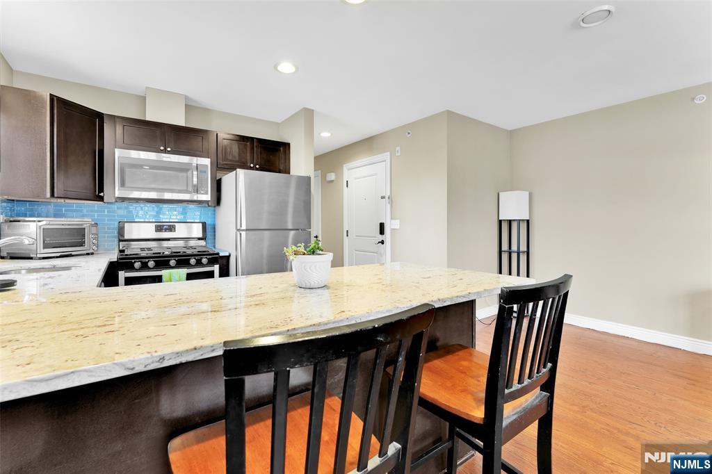 210 Hackensack Street Wood-Ridge, NJ 07075 - Photo 6 of 15 a kitchen with stainless steel appliances granite countertop a table chairs sink and cabinets
