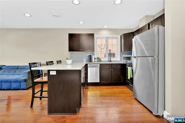 a kitchen with stainless steel appliances granite countertop a refrigerator a sink a stove and a microwave