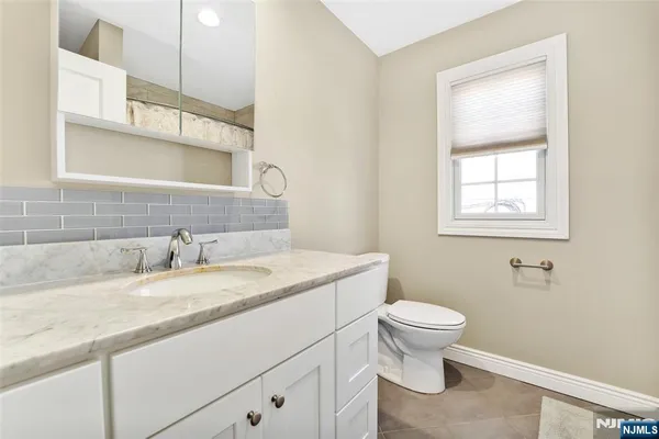 a bathroom with a granite countertop toilet sink and mirror