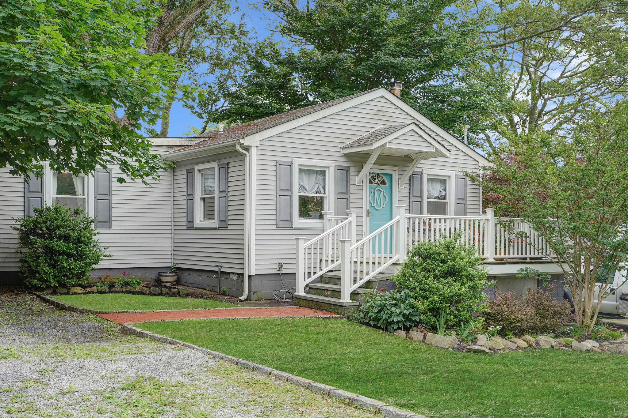 a view of a house with a yard plants and large tree