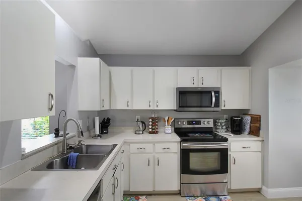 a kitchen with stainless steel appliances granite countertop a sink a stove a refrigerator and white cabinets