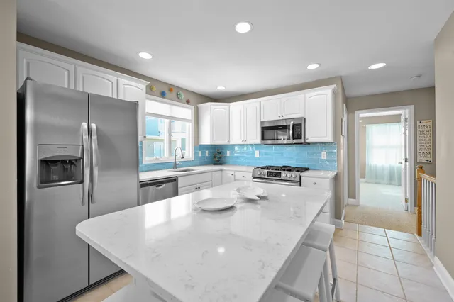 a kitchen with stainless steel appliances granite countertop a refrigerator a stove and a sink with wooden floor