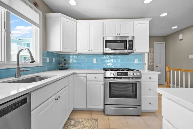 a kitchen with granite countertop white cabinets and white stainless steel appliances