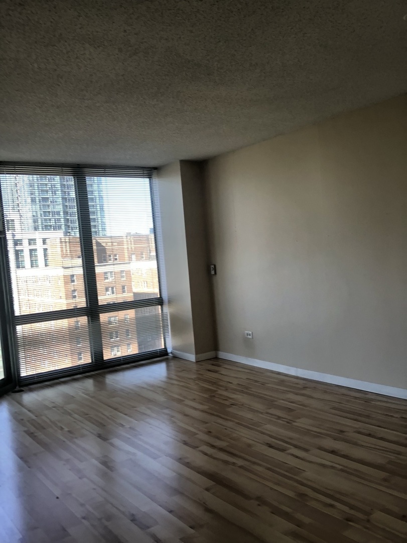 111 West Maple Street, Unit 1309 Chicago, IL 60610 - Photo 9 of 14 a view of an empty room with wooden floor and a window