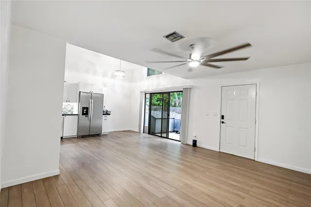 an empty room with wooden floor fan and windows