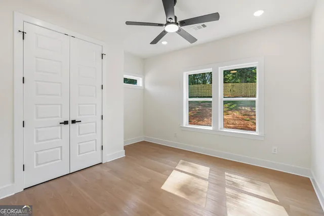 an empty room with wooden floor and ceiling fan
