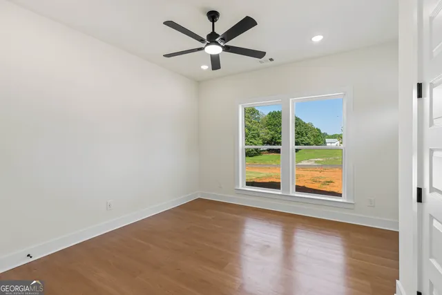 an empty room with wooden floor closet and windows