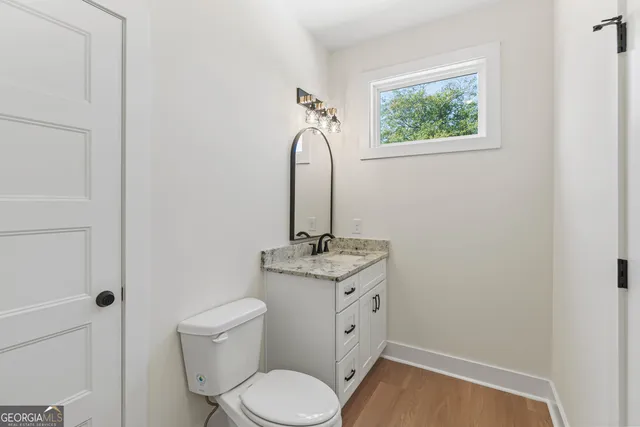 a bathroom with a granite countertop sink toilet and vanity
