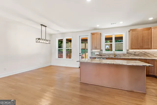 a large kitchen with a lot of kitchen island a sink wooden floor and a large window