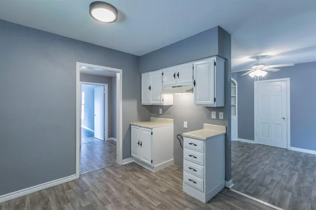 a view of cabinets a wooden floor and a window in a room