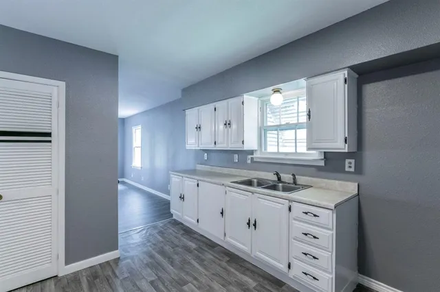 a kitchen with white cabinets and window