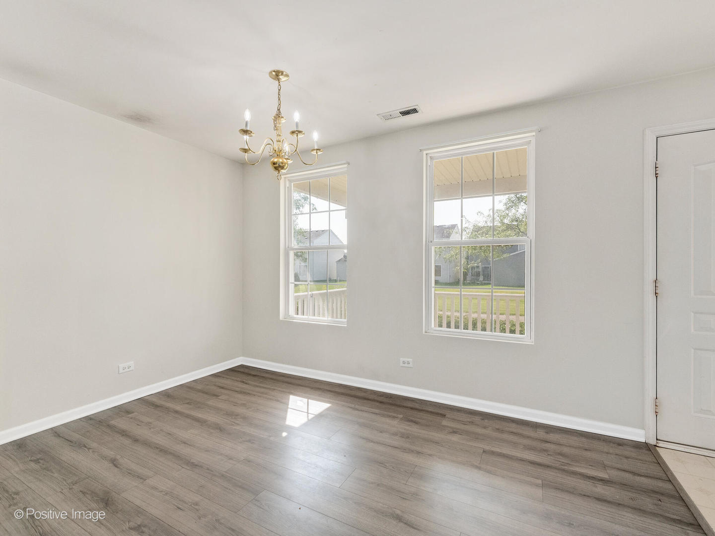 948 Symphony Drive Aurora, IL 60504 - Photo 5 of 22 an empty room with wooden floor chandelier and windows