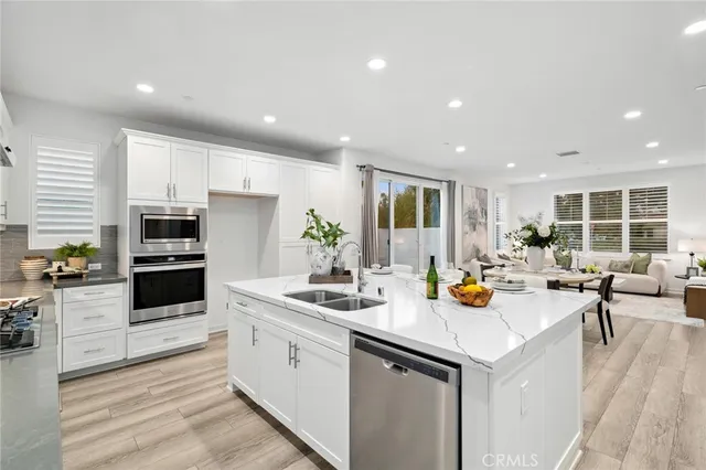 a kitchen with a sink stainless steel appliances furniture cabinets and a wooden floor