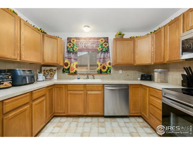 a kitchen with stainless steel appliances a sink a stove a refrigerator cabinets and a window