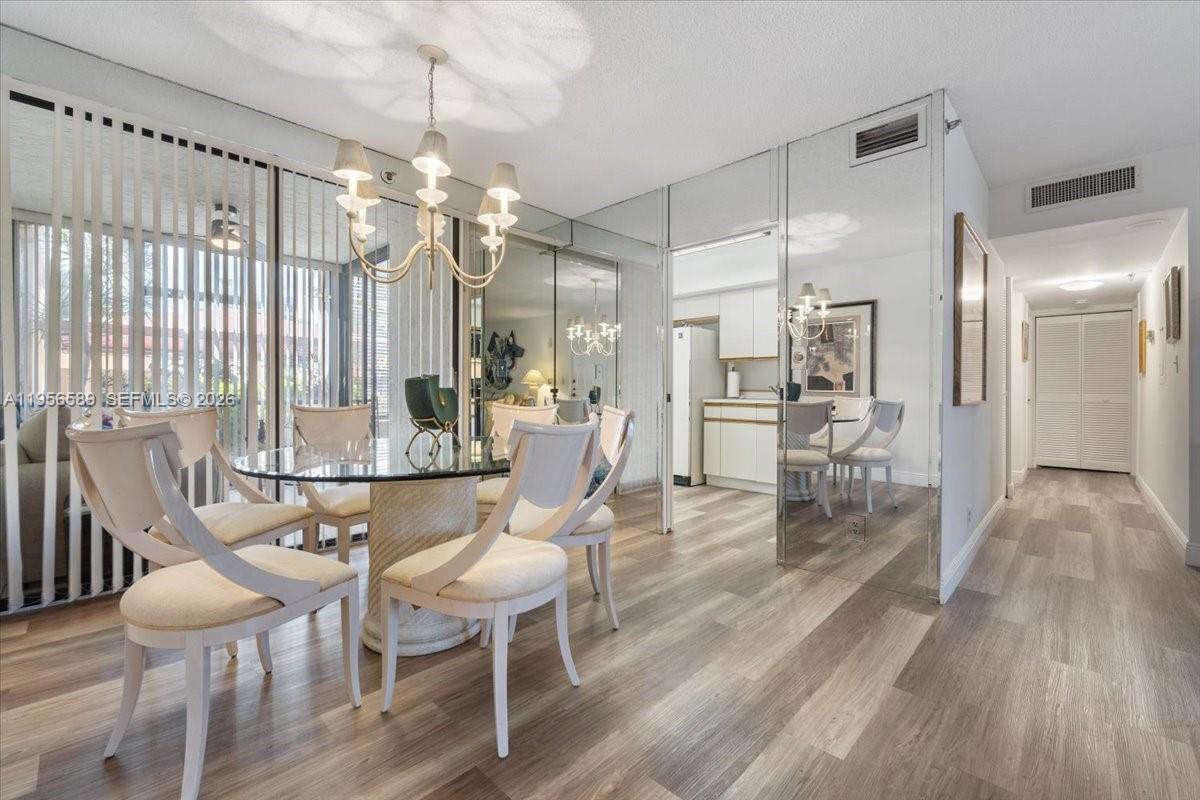 7201 Promenade Drive, Unit 101 Boca Raton, FL 33433 - Photo 13 of 54 a dining room with furniture a chandelier and wooden floor