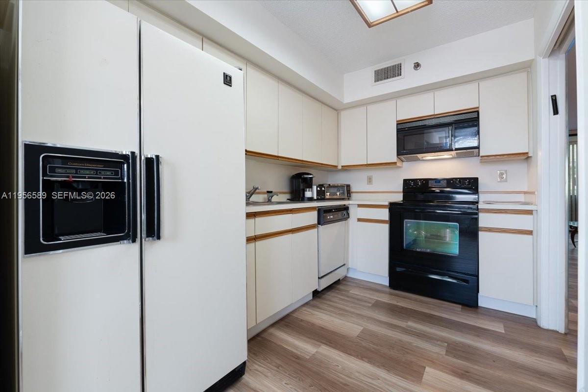 7201 Promenade Drive, Unit 101 Boca Raton, FL 33433 - Photo 16 of 54 a kitchen with white cabinets and stainless steel appliances
