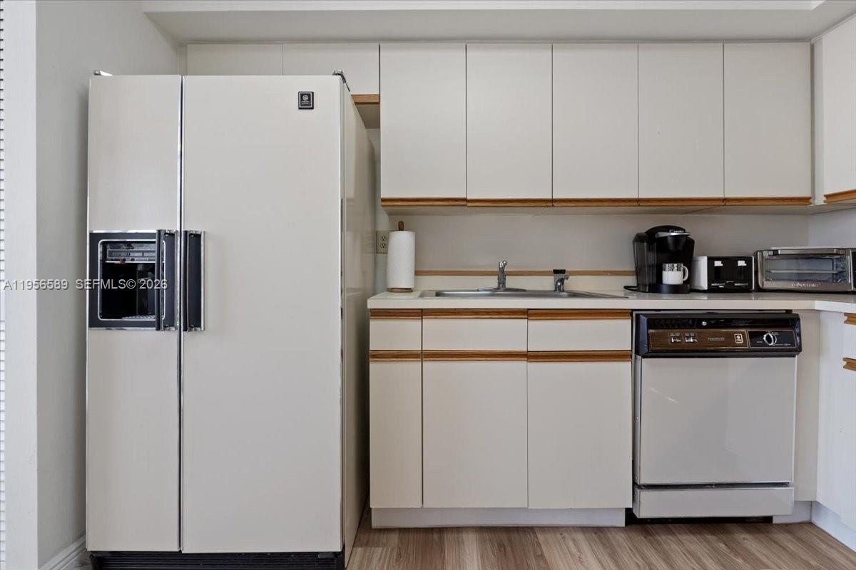 7201 Promenade Drive, Unit 101 Boca Raton, FL 33433 - Photo 18 of 54 a kitchen with stainless steel appliances white cabinets and a refrigerator