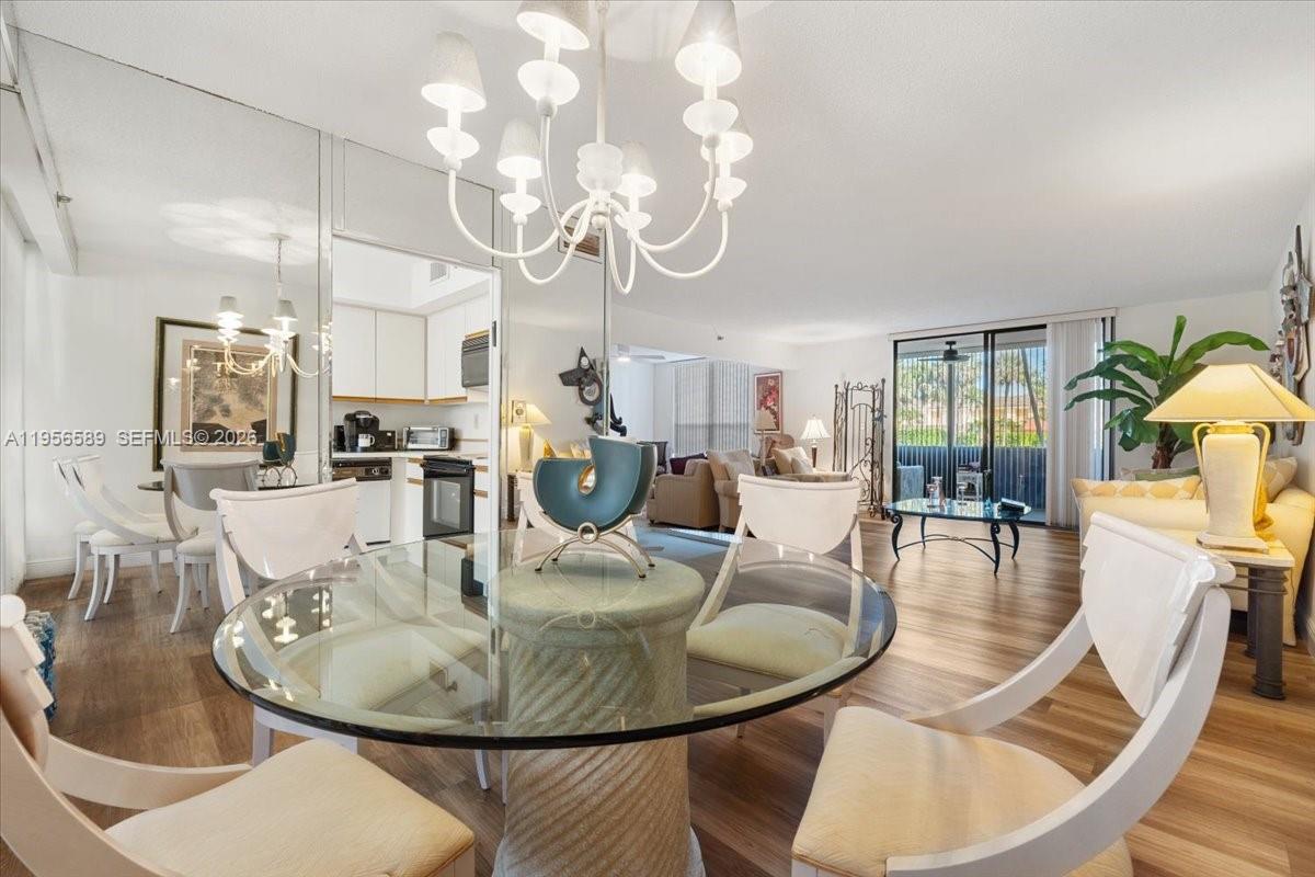 7201 Promenade Drive, Unit 101 Boca Raton, FL 33433 - Photo 2 of 54 a dining room with wooden floor a chandelier a wooden table and chairs