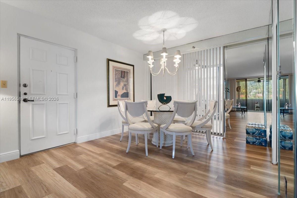 7201 Promenade Drive, Unit 101 Boca Raton, FL 33433 - Photo 7 of 54 a view of a dining room with furniture wooden floor and chandelier