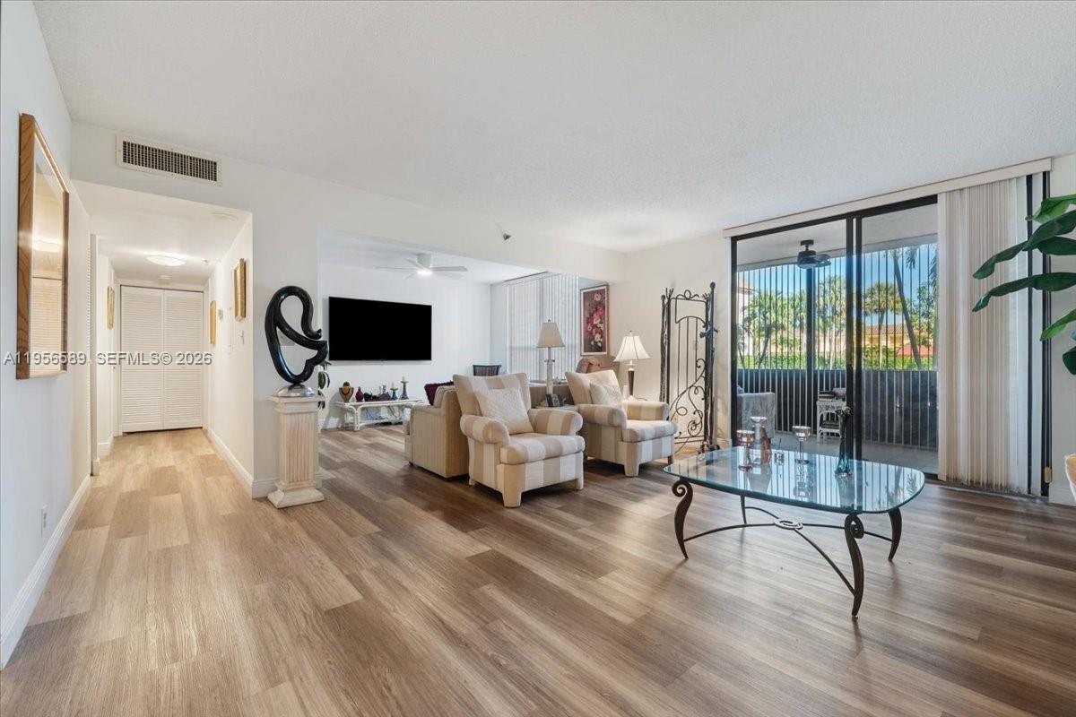 7201 Promenade Drive, Unit 101 Boca Raton, FL 33433 - Photo 10 of 54 a living room with furniture a flat screen tv and a floor to ceiling window