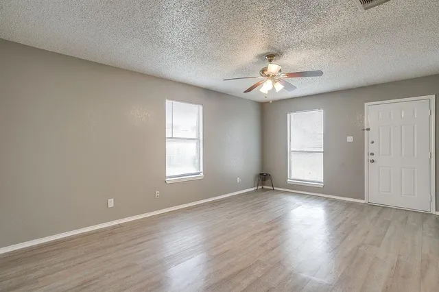 an empty room with wooden floor and windows