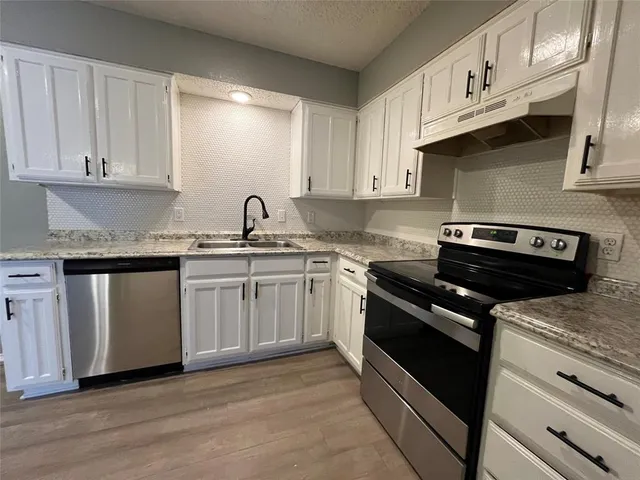 a kitchen with granite countertop a sink a stove and cabinets