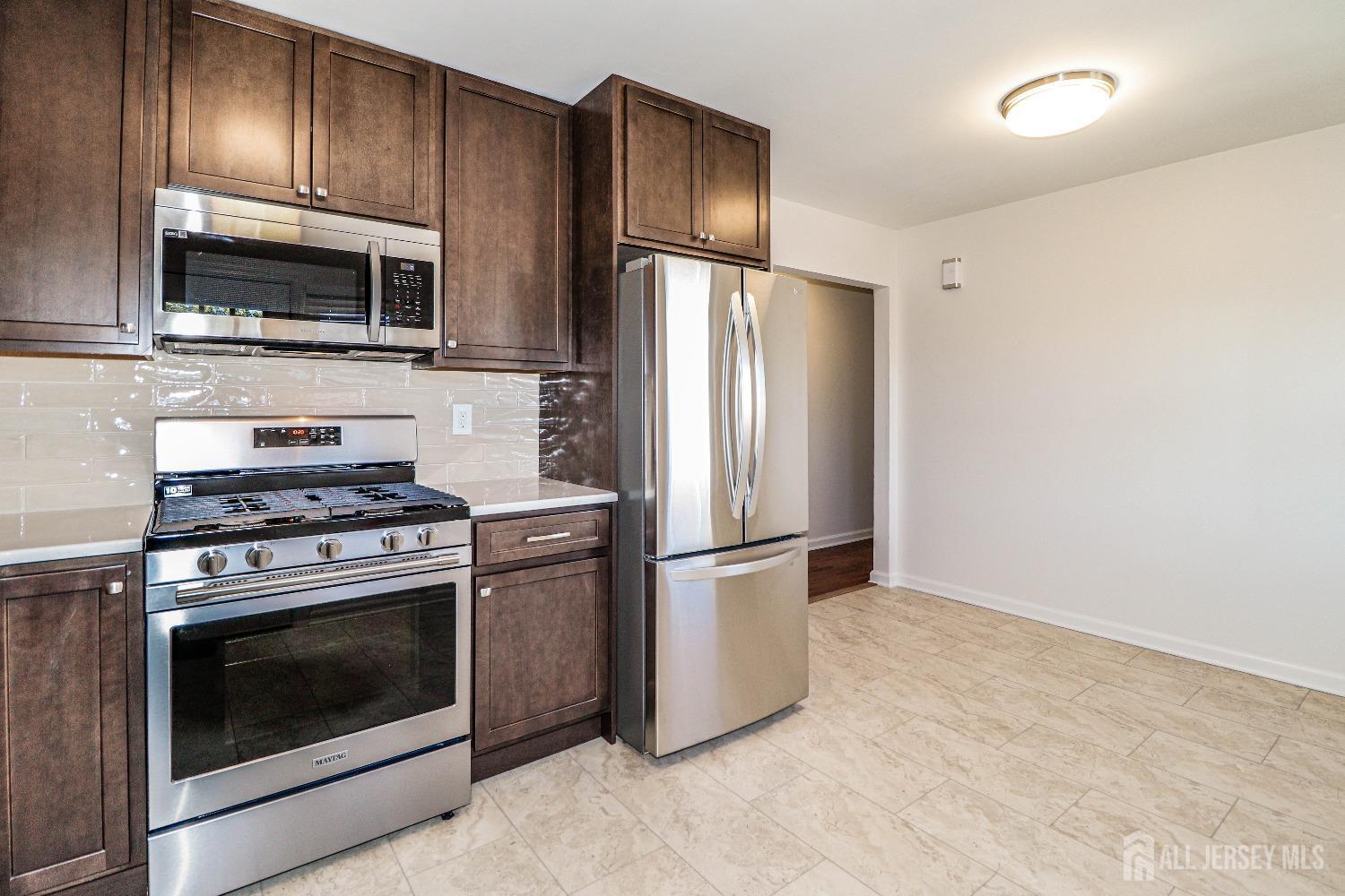 298 Central Avenue, Unit 4A Edison, NJ 08817 - Photo 3 of 12 a kitchen with stainless steel appliances granite countertop a stove microwave and refrigerator