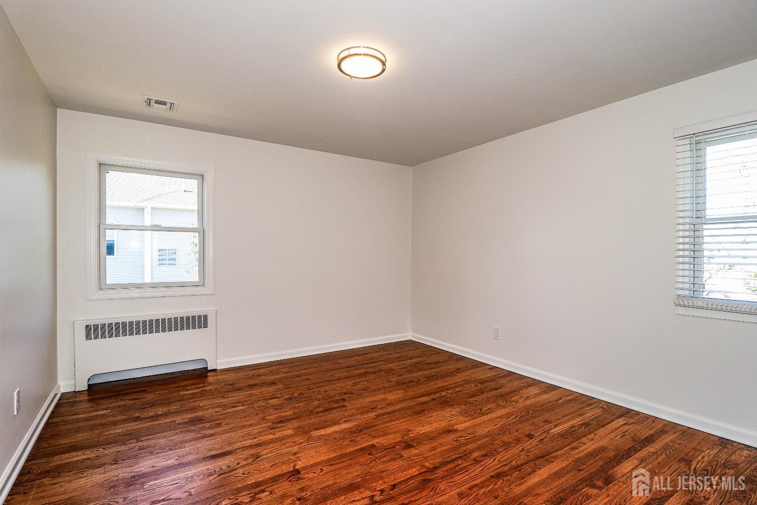 298 Central Avenue, Unit 4A Edison, NJ 08817 - Photo 9 of 12 an empty room with wooden floor and windows