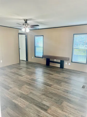 a view of an empty room with window a ceiling fan and wooden floor
