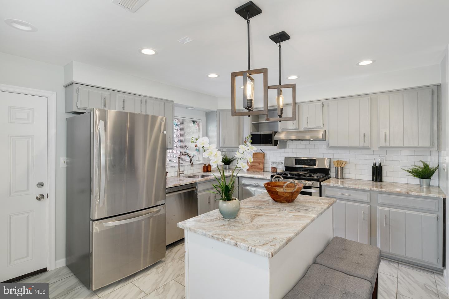 a kitchen with stainless steel appliances granite countertop a refrigerator a stove a sink dishwasher a refrigerator and white cabinets with wooden floor