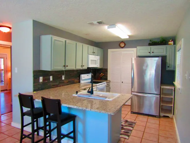 a kitchen with stainless steel appliances granite countertop a sink refrigerator and cabinets