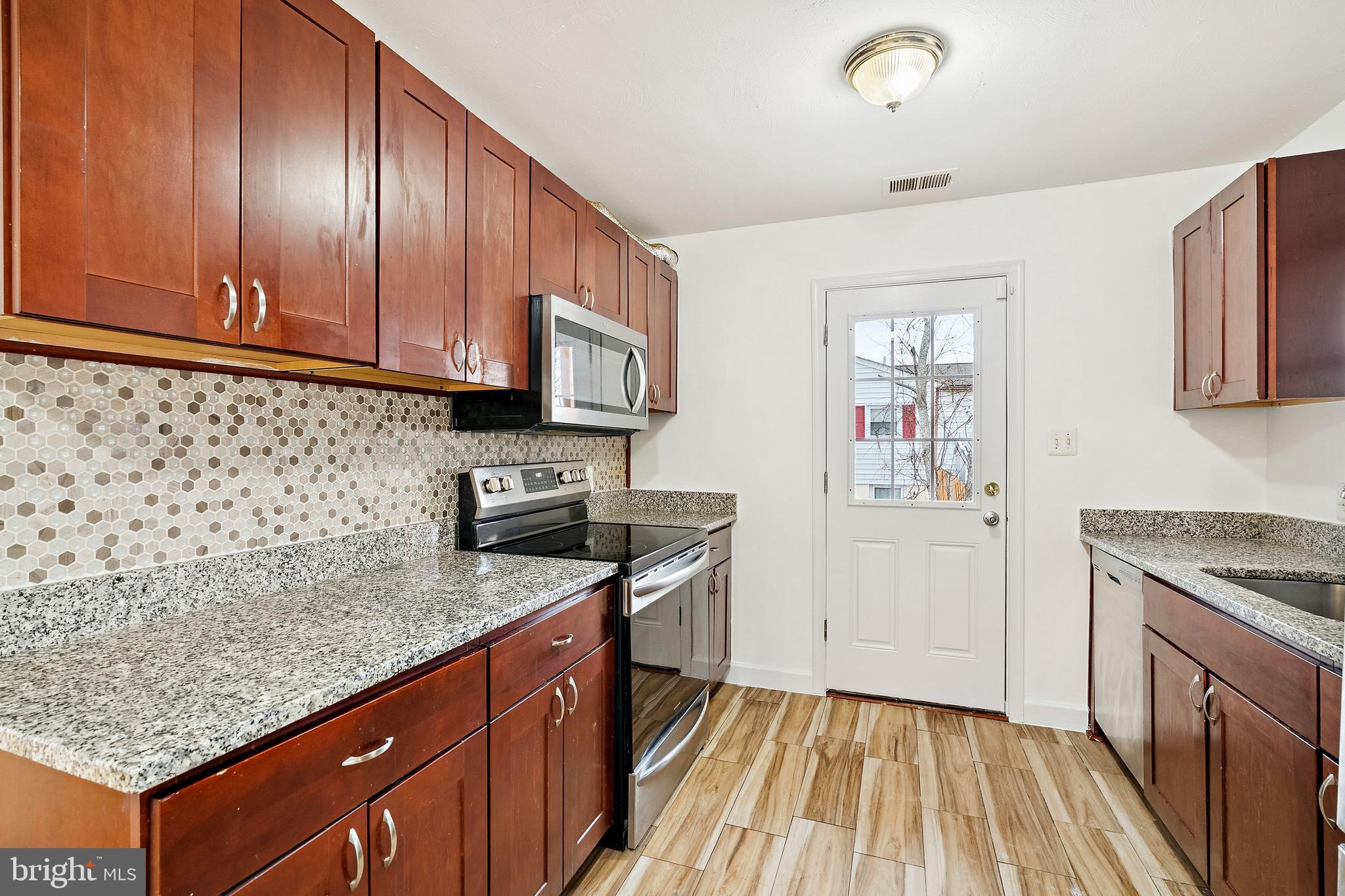 14508 Fullerton Road Woodbridge, VA 22193 - Photo 10 of 28 a kitchen with granite countertop wooden cabinets and white appliances