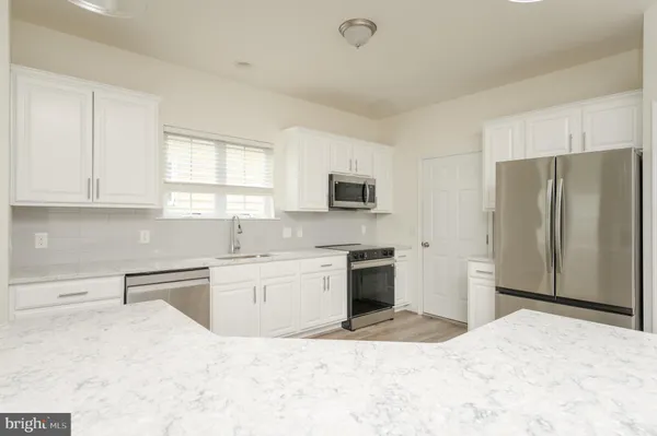 a kitchen with granite countertop a refrigerator stove top oven and sink
