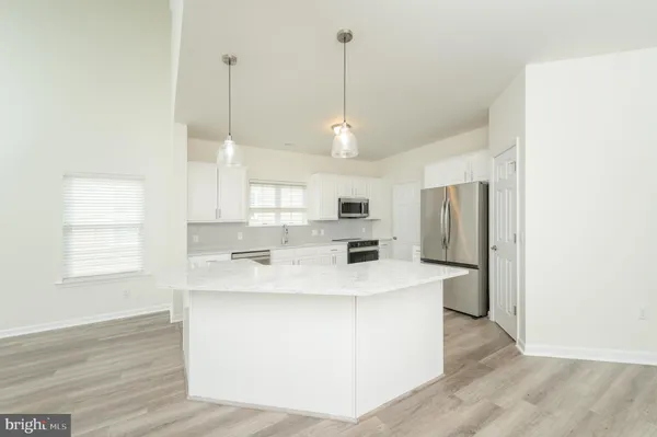 a large kitchen with stainless steel appliances kitchen island a large counter top space a sink wooden floor and a window