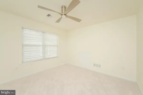 an empty room with a window and a ceiling fan