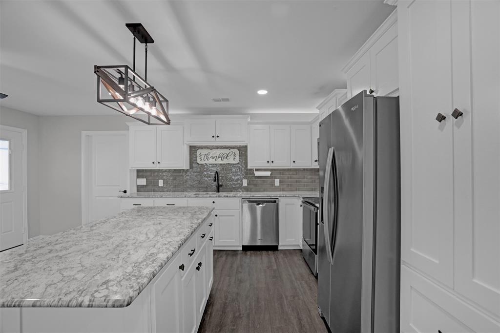 399 South Main Street Blue Ridge, TX 75424 - Photo 8 of 25 a kitchen with stainless steel appliances granite countertop a refrigerator a sink dishwasher a stove and a dining table with wooden floor