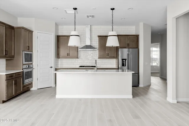 a large kitchen with stainless steel appliances granite countertop a refrigerator a oven and a wooden floors