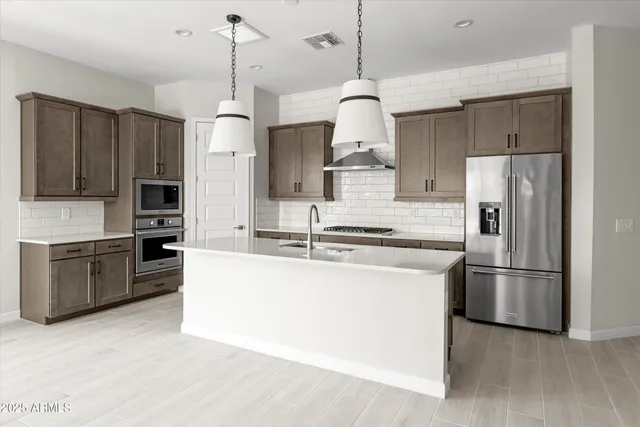 a kitchen with stainless steel appliances granite countertop a refrigerator a stove a sink and a refrigerator