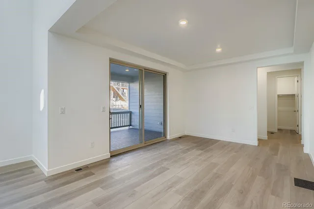 an empty room with wooden floor and mirror
