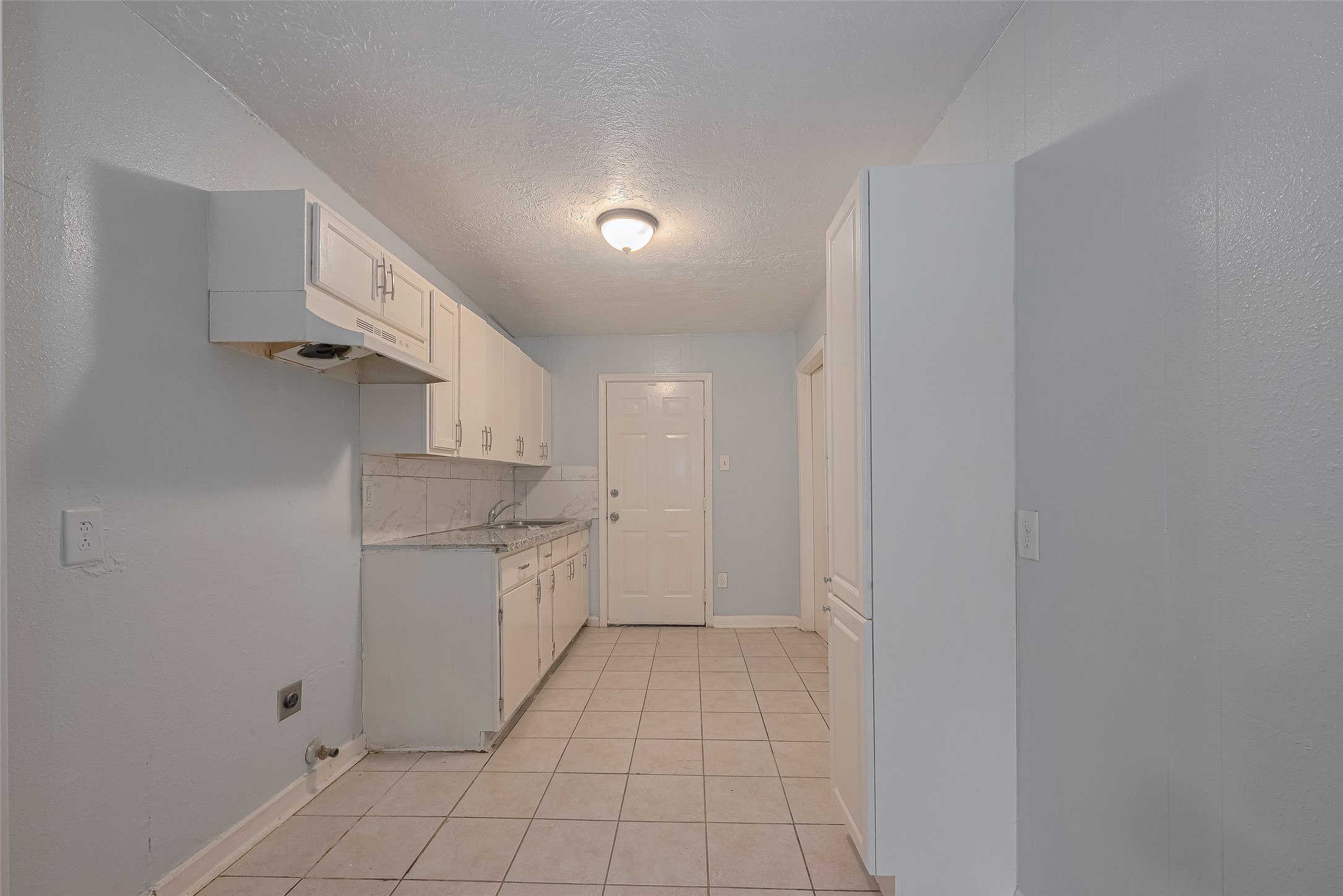 4906 Larkspur Street Houston, TX 77033 - Photo 4 of 14 a kitchen with white cabinets and white appliances