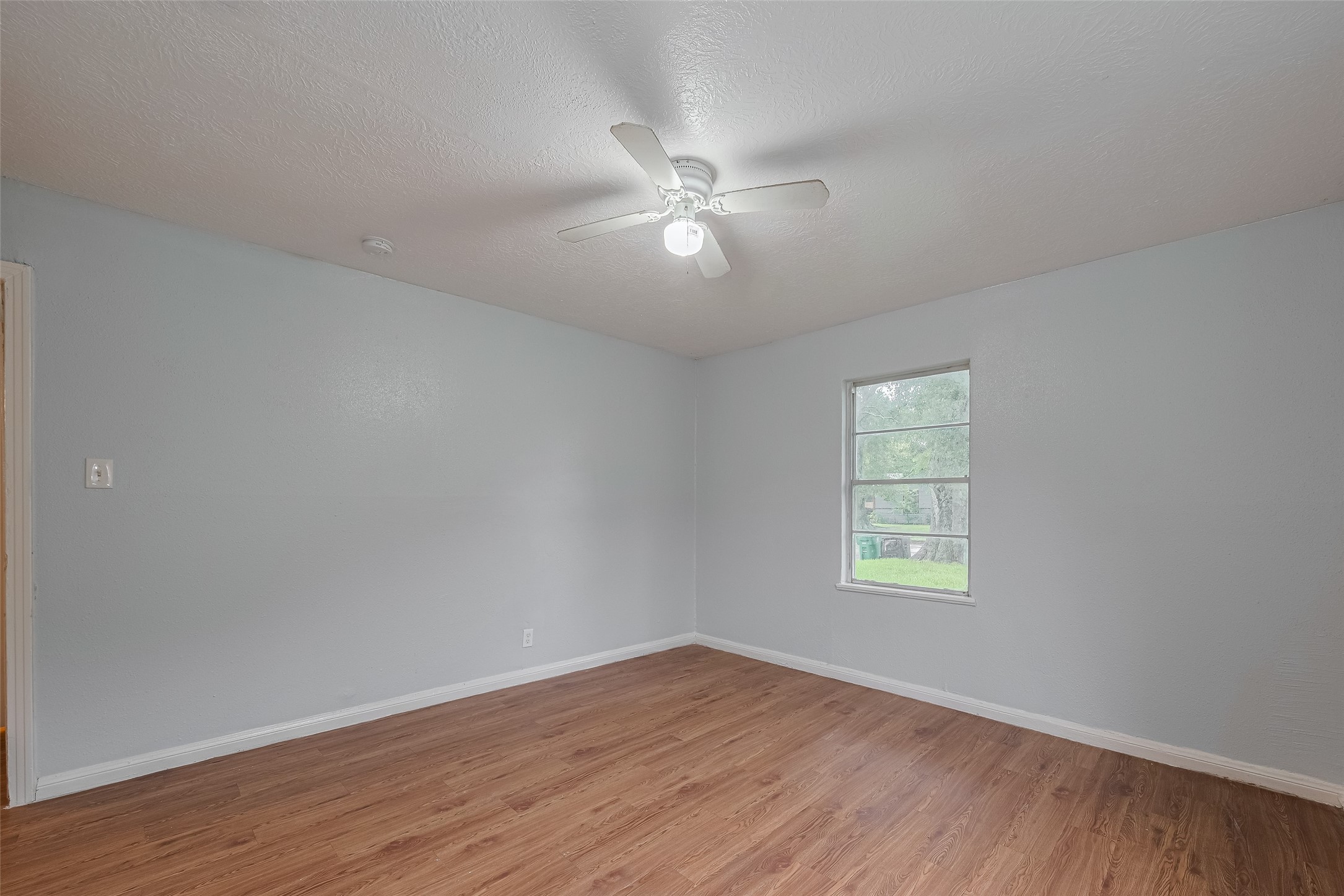 4906 Larkspur Street Houston, TX 77033 - Photo 7 of 14 an empty room with wooden floor ceiling fan and windows