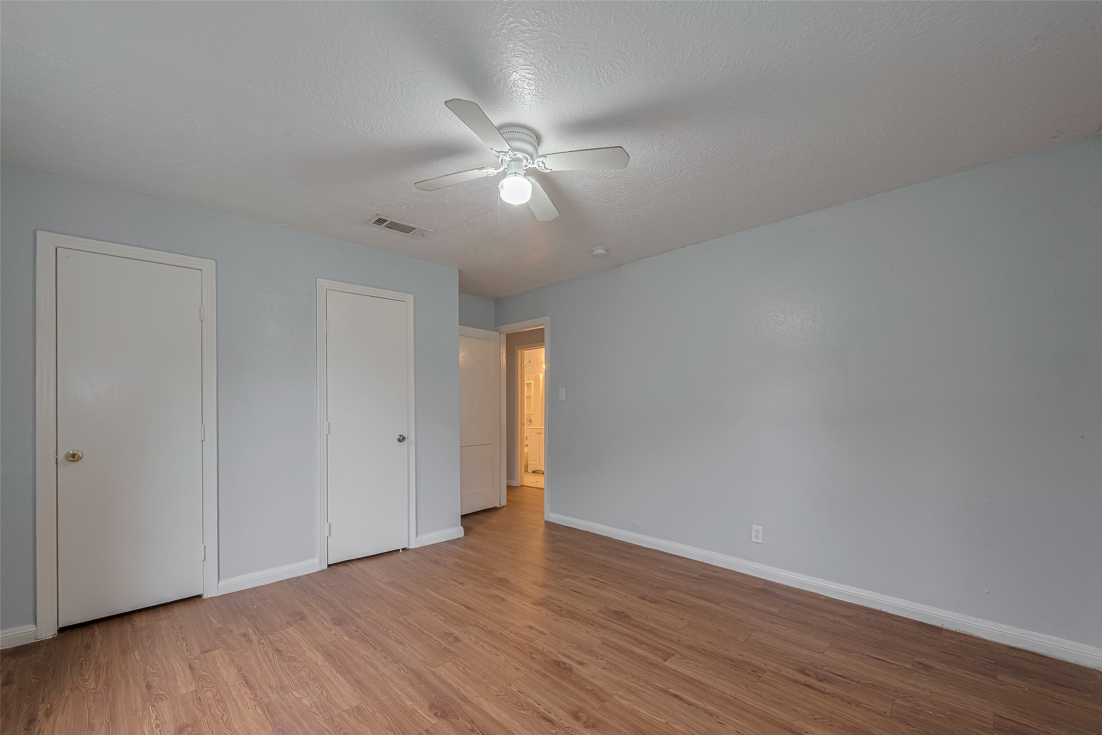 4906 Larkspur Street Houston, TX 77033 - Photo 8 of 14 a view of an empty room with wooden floor and a ceiling fan