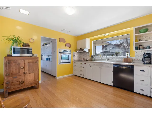 a kitchen with stainless steel appliances white cabinets and wooden floor