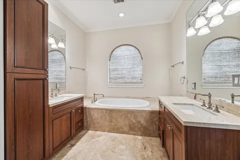 a bathroom with a tub double vanity sink and mirror