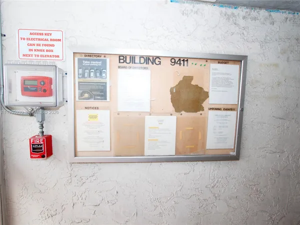 a view of a tall white building next to a yard with palm trees