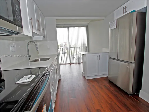 a kitchen with kitchen island wooden floors appliances and sink