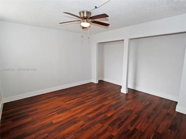 a view of a room with wooden floor and a ceiling fan