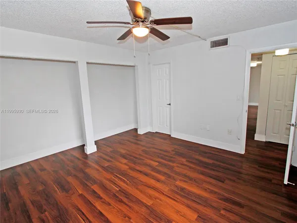 an empty room with wooden floor fan and windows