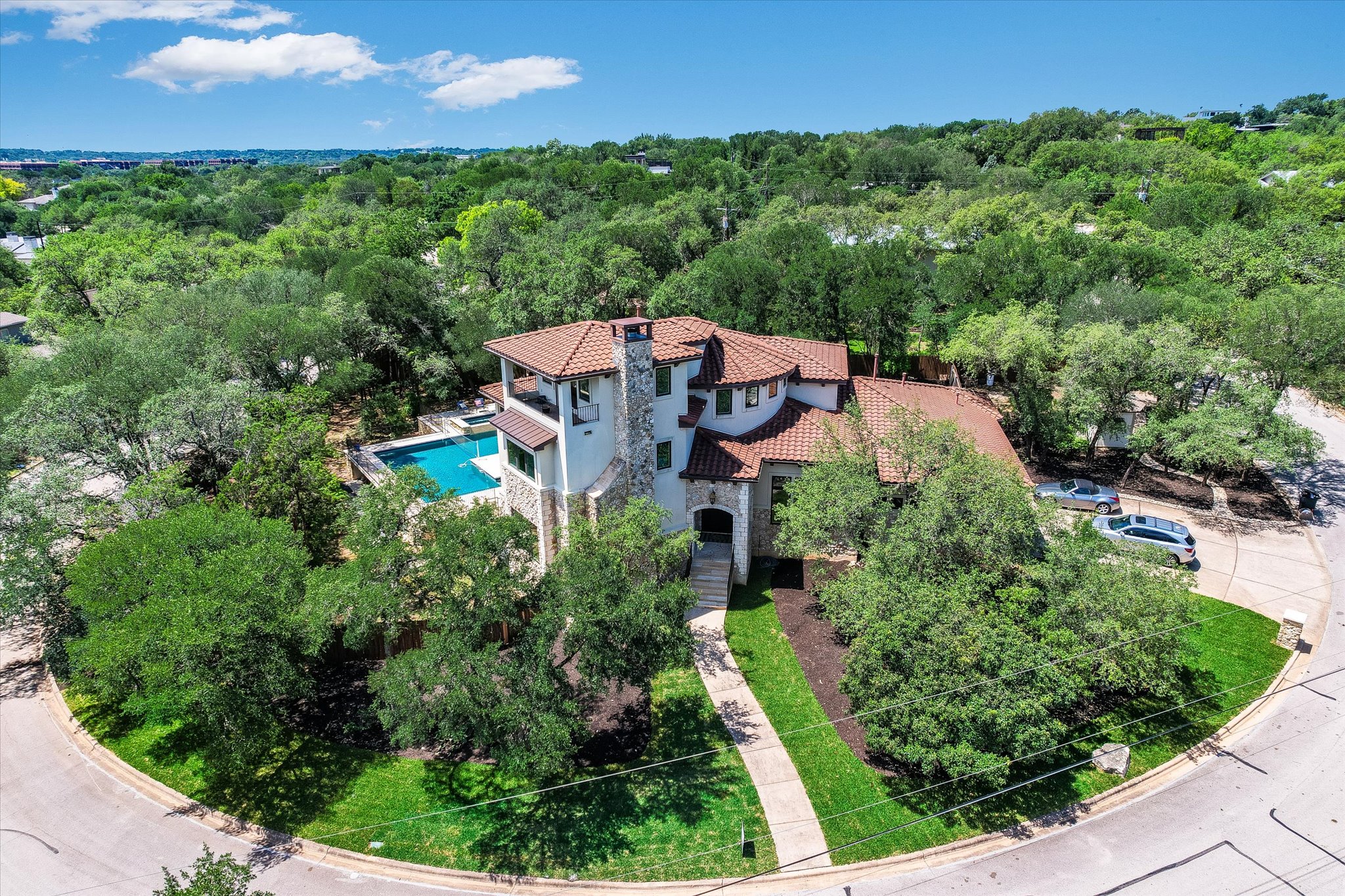 11 Inwood Circle Austin, TX 78746 - Photo 3 of 38 A terracotta-roofed residence nestled amongst lush trees, featuring a serene backyard pool and inviting curb appeal.