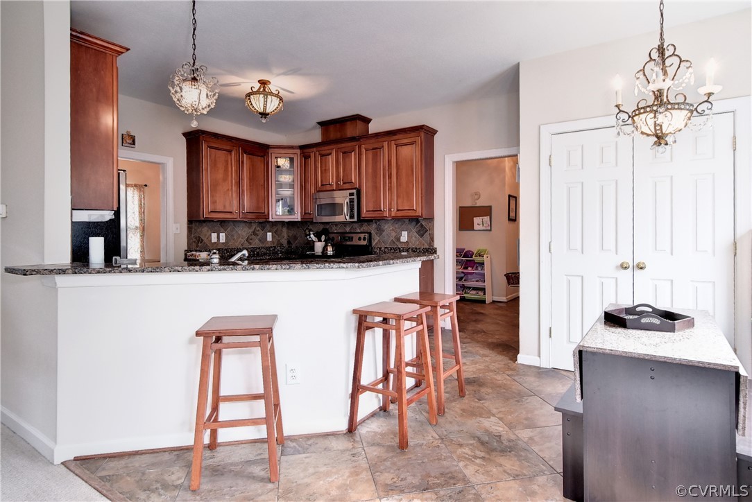 3986 Bournemouth Bend Williamsburg, VA 23188 - Photo 11 of 47 a kitchen with stainless steel appliances granite countertop a stove top oven a refrigerator a sink and a dining table with chairs